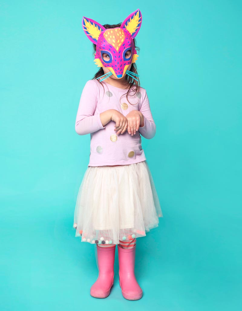 Girl in a colorful paper alebrije fox mask